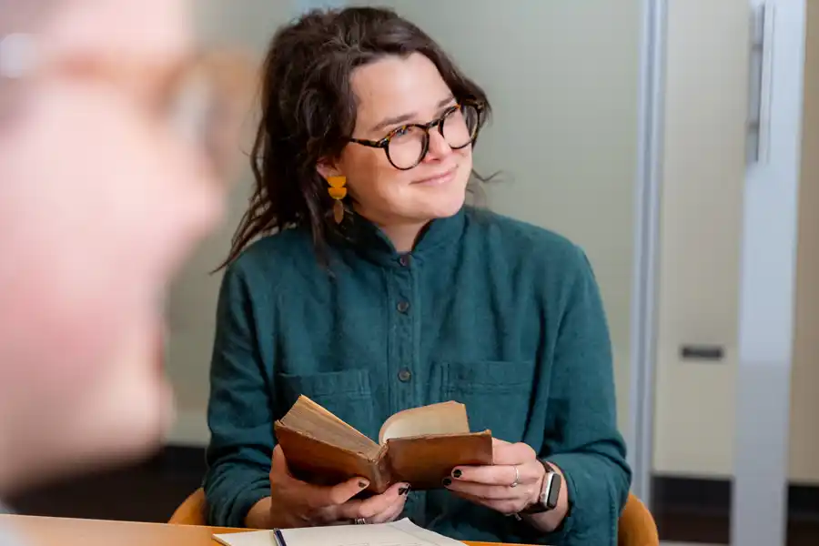 An image of a woman engaged in class, holding a book