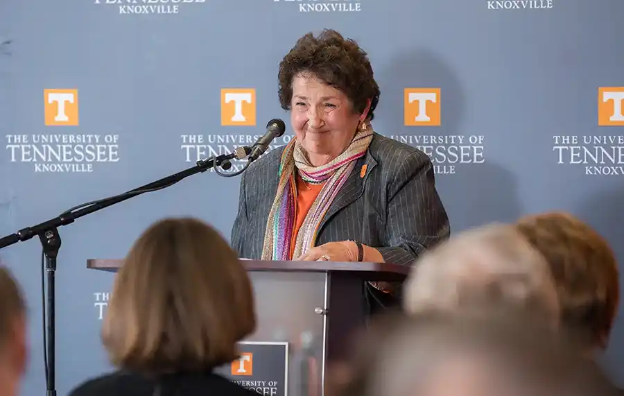 A woman speaks at a podium with UTK logos behind her