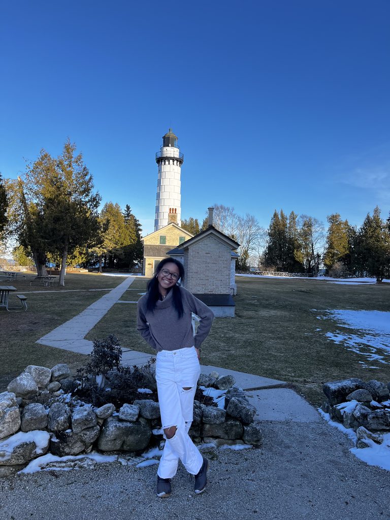 Keria Wilcox stands outside with a lighthouse in the distance.